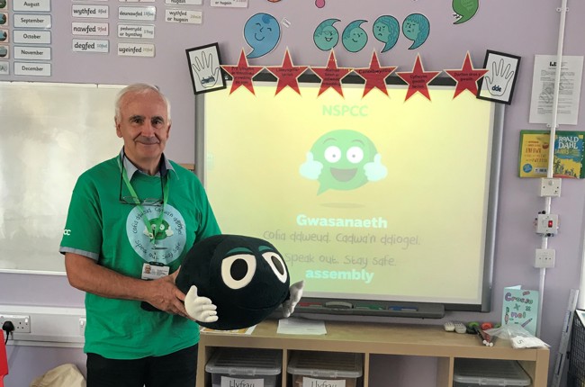 Gwirfoddolwr yr NSPCC yn sefyll mewn ystafell ddosbarth