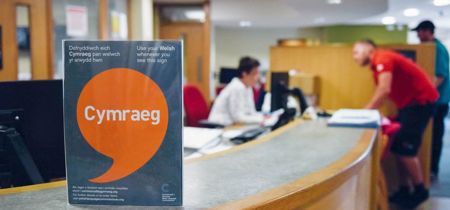 Poster Iaith Gwaith ar ddesg y dderbynfa 